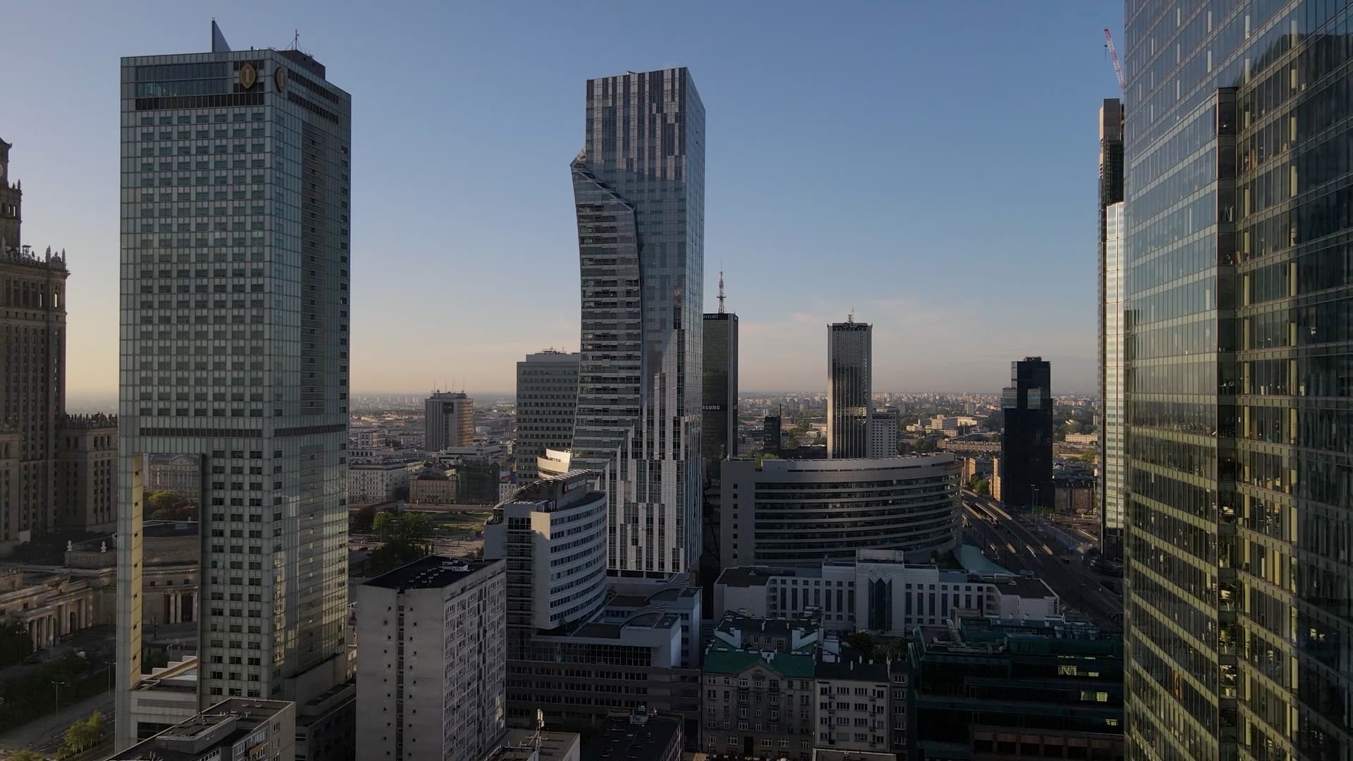 Vue aérienne d'un quartier d'affaires en lumière rasante : tours de bureaux vitrées et immeubles en contrebas