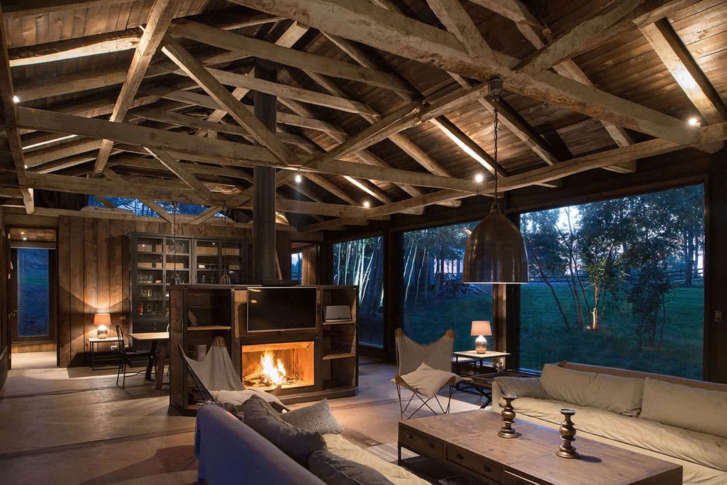 Intérieur de grange rénovée par CUBEO : charpente d'origine conservée apparente et séjour contemporain