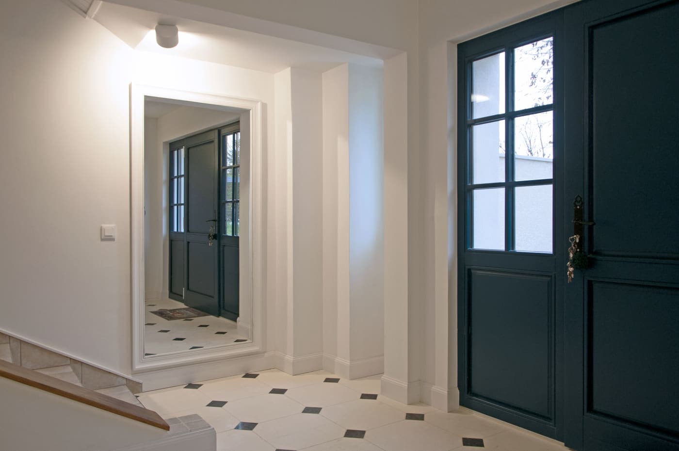 Entrée avec double porte vitrée bleue et sol carreaux de ciment