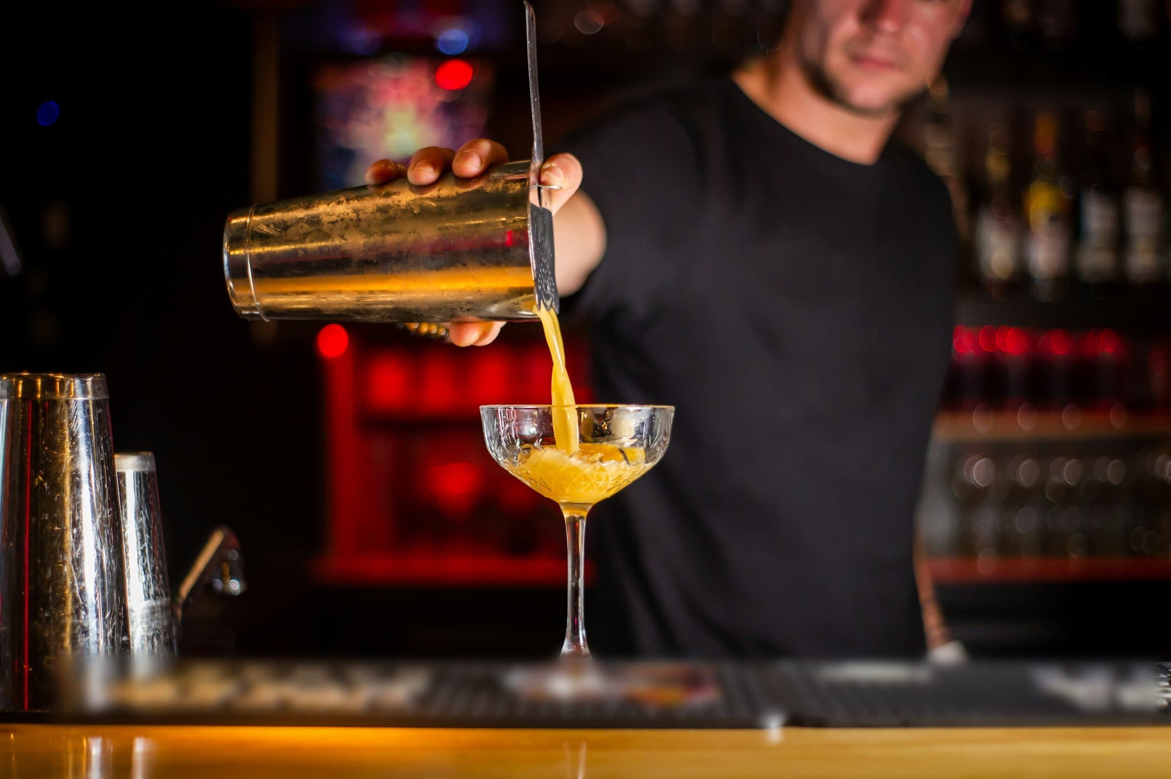 Barman qui verse un cocktail ambré au comptoir