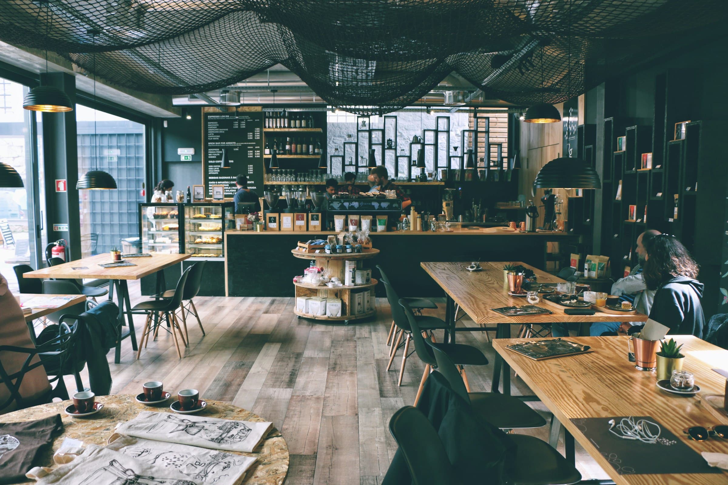 Café-restaurant aux grandes tables de bois et comptoir en fond de salle