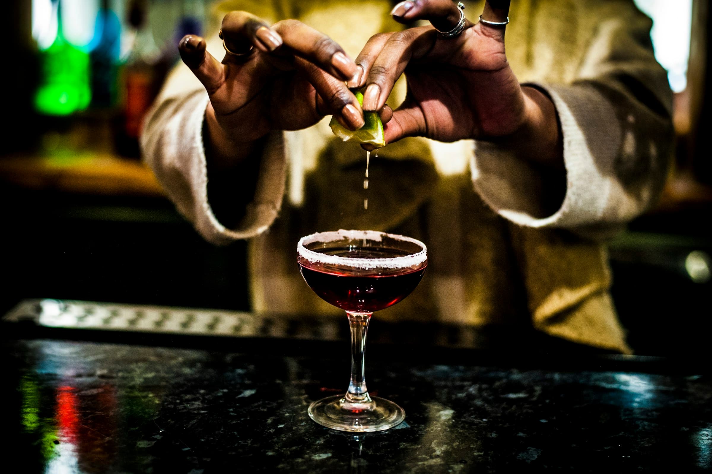 Barman qui presse un citron vert au-dessus d'un cocktail