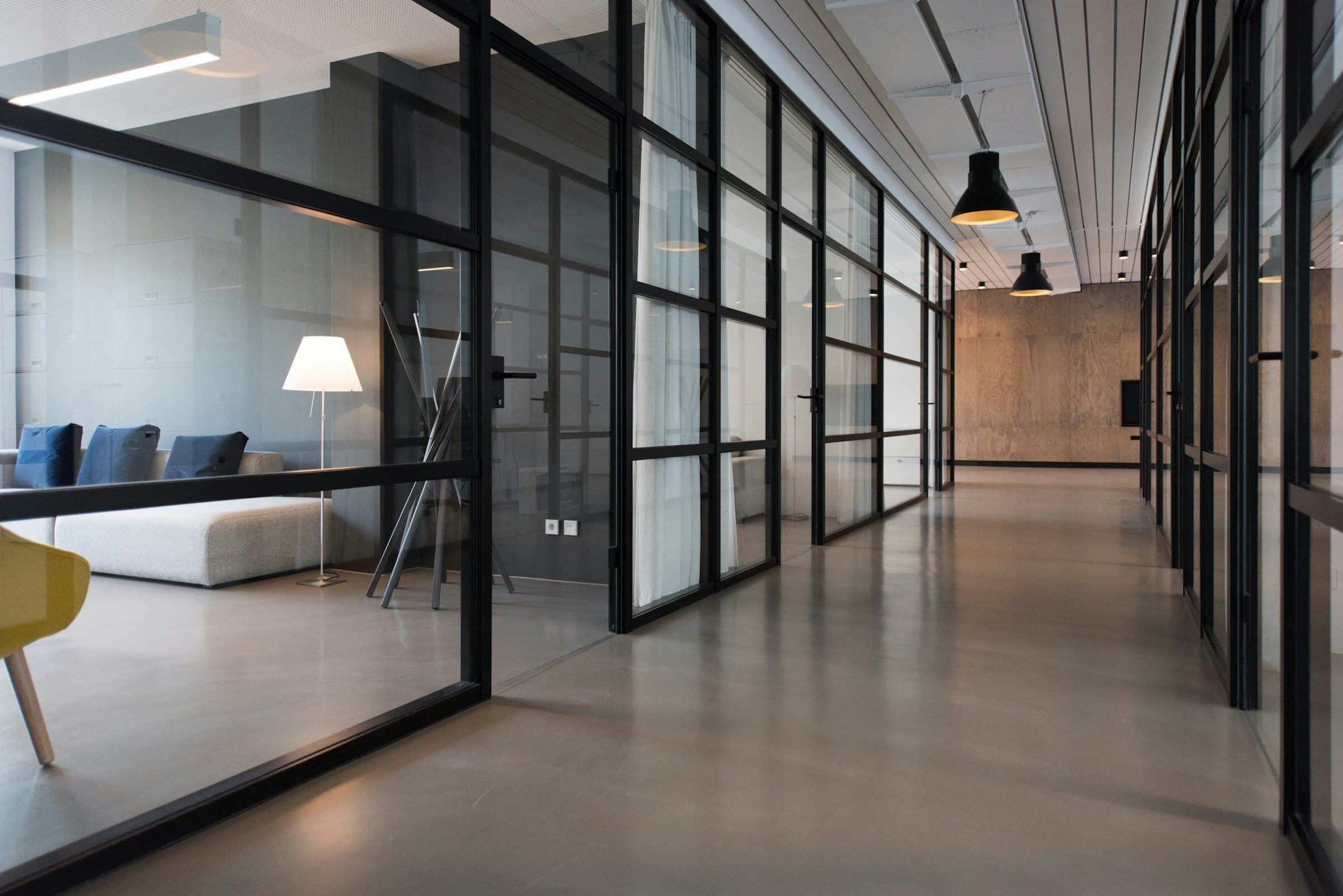 Couloir bordé de bureaux aux cloisons vitrées à profilés noirs