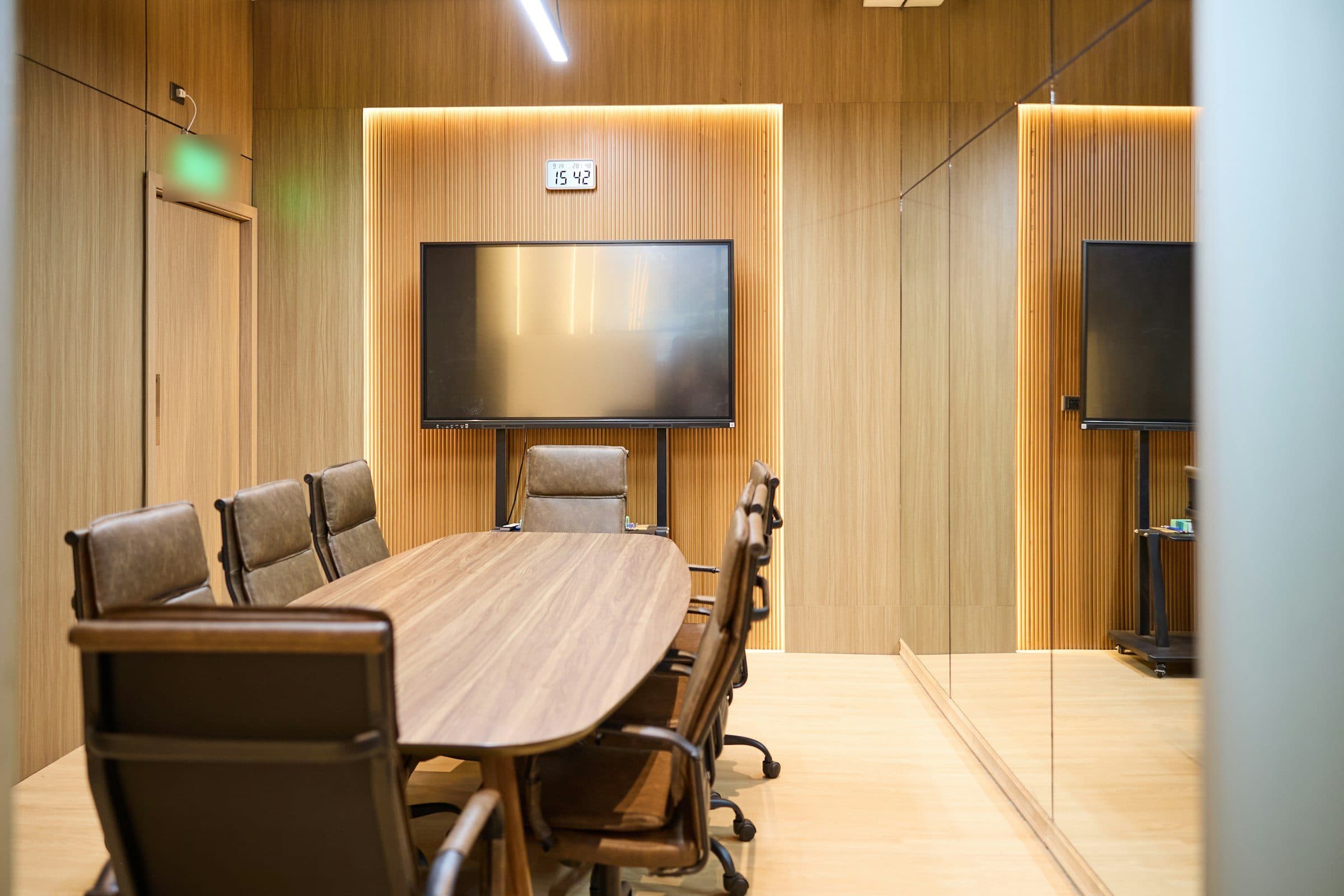 Salle de réunion habillée de bois, table ovale et écran mural