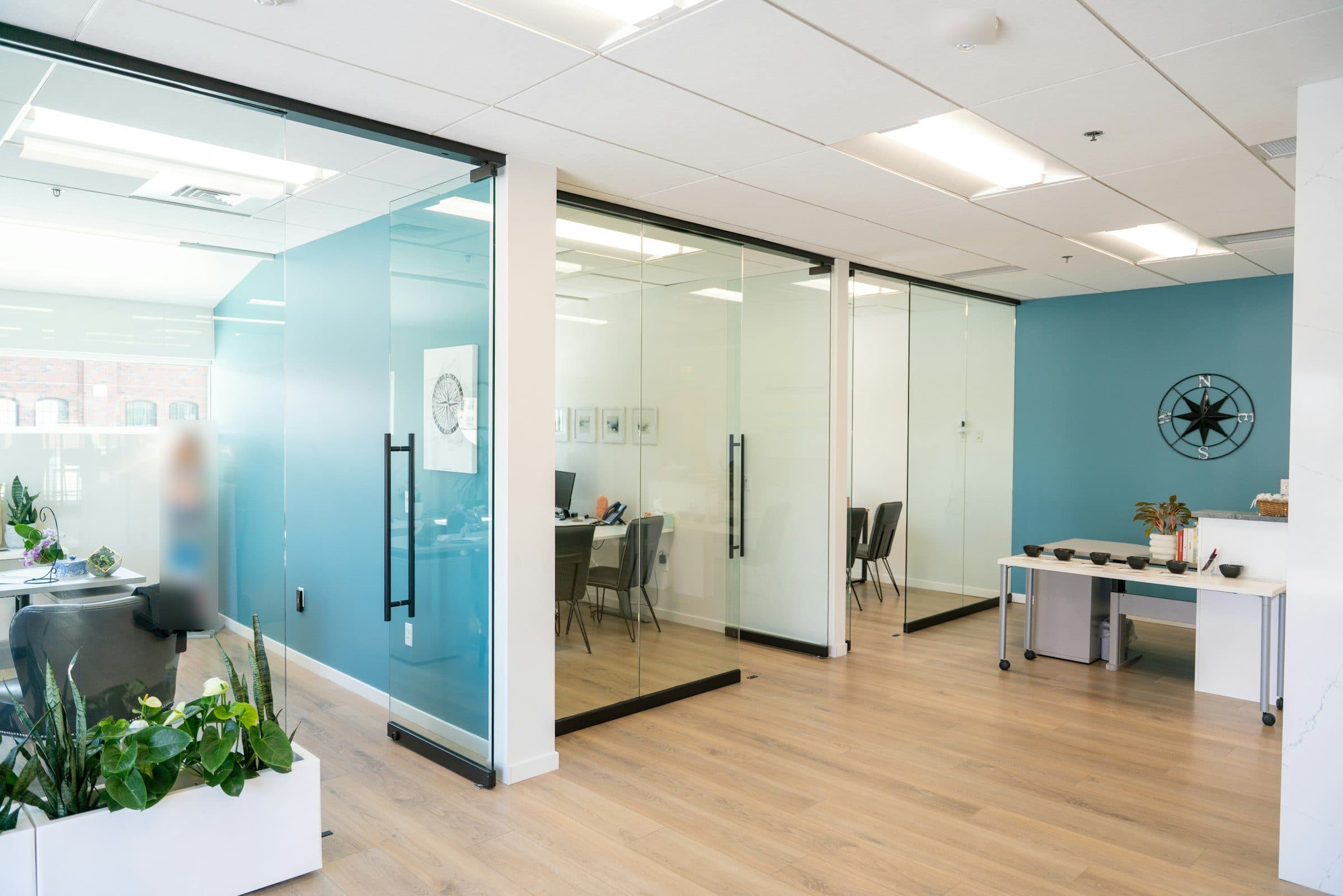 Bureaux fermés par des cloisons vitrées toute hauteur, mur bleu et parquet clair