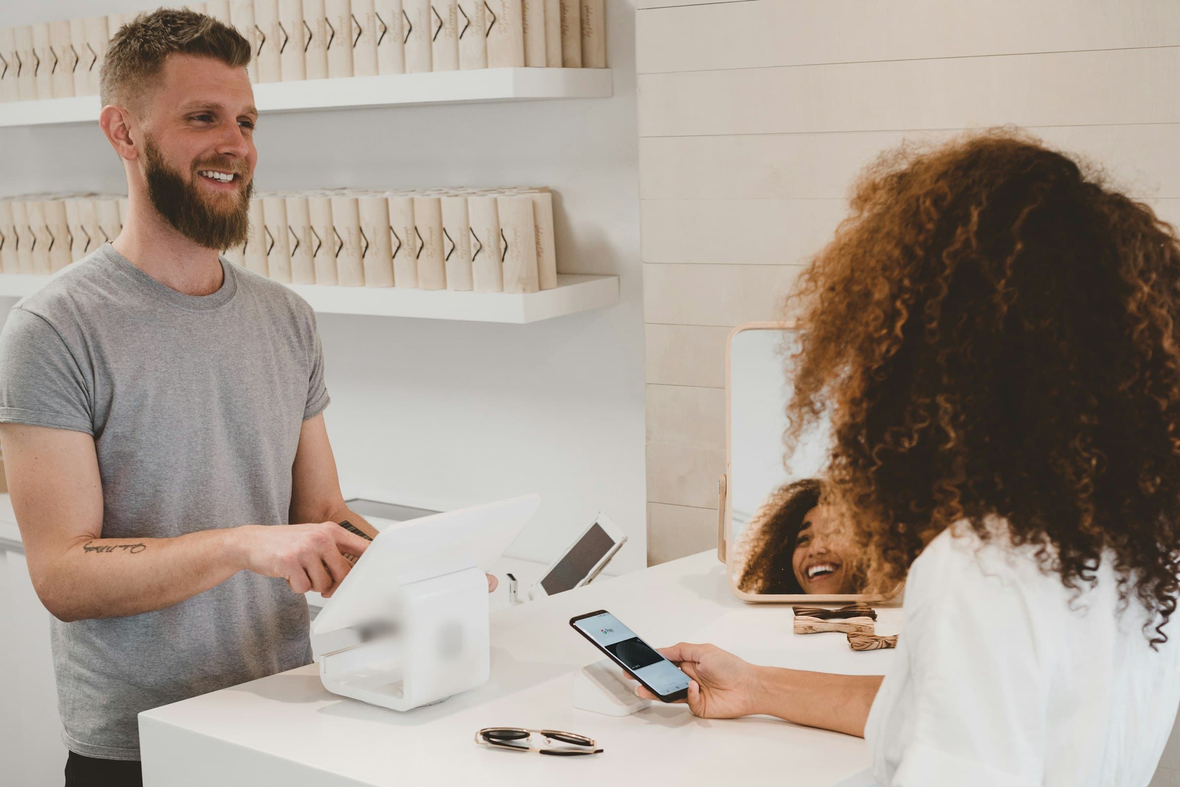 Commerçant souriant qui encaisse une cliente au comptoir de sa boutique