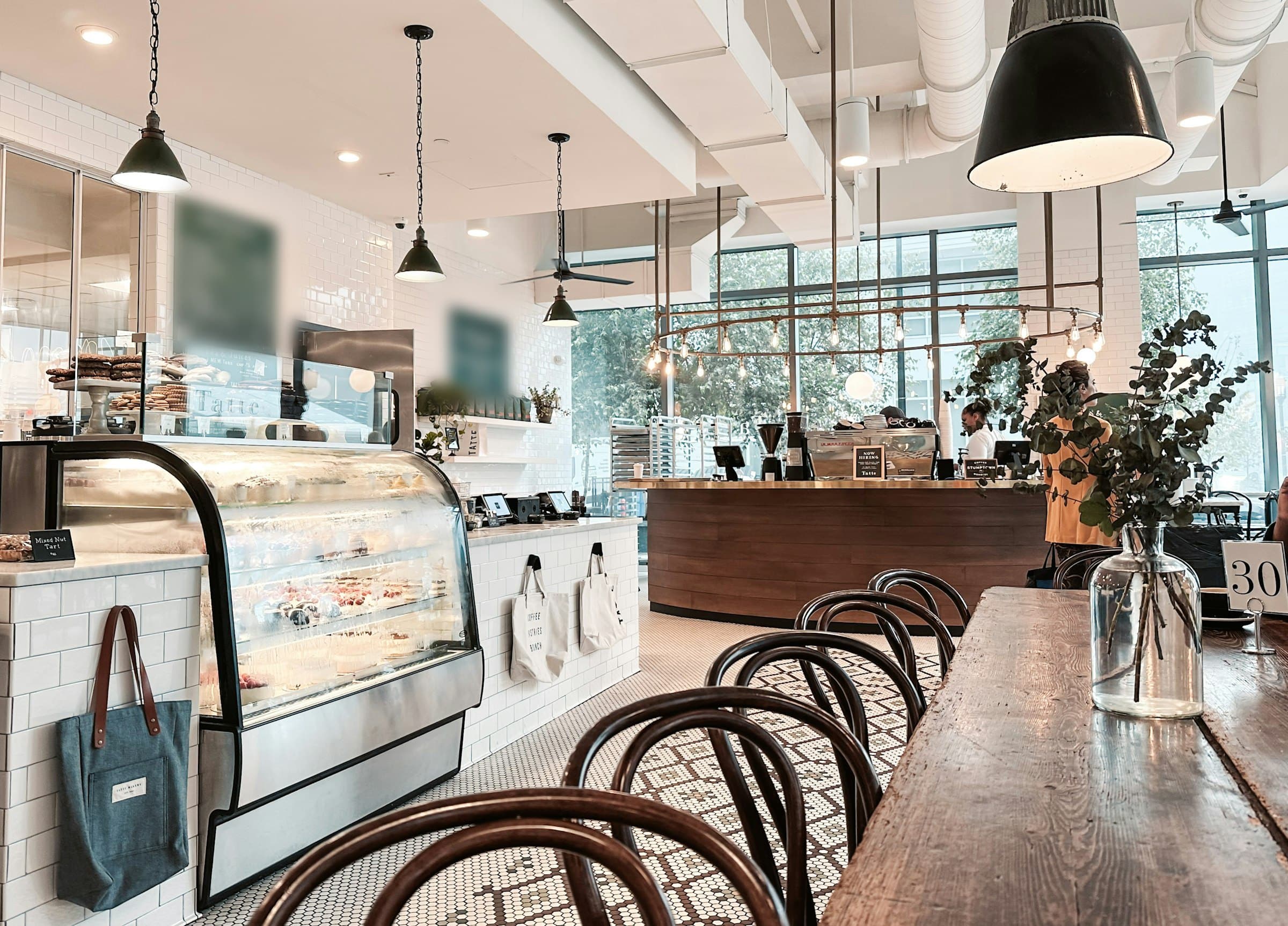 Boulangerie-café lumineuse, vitrine réfrigérée et grande table d'hôtes