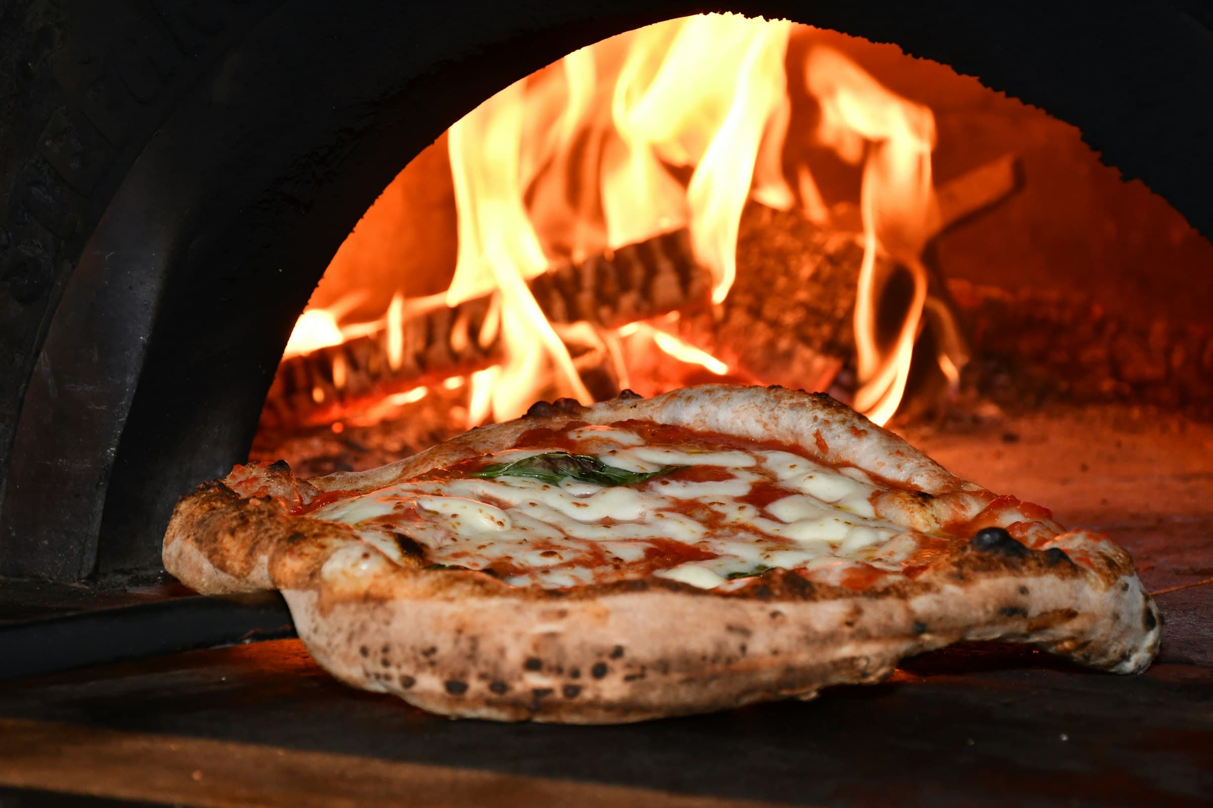 Pizza napolitaine qui cuit dans un four à bois