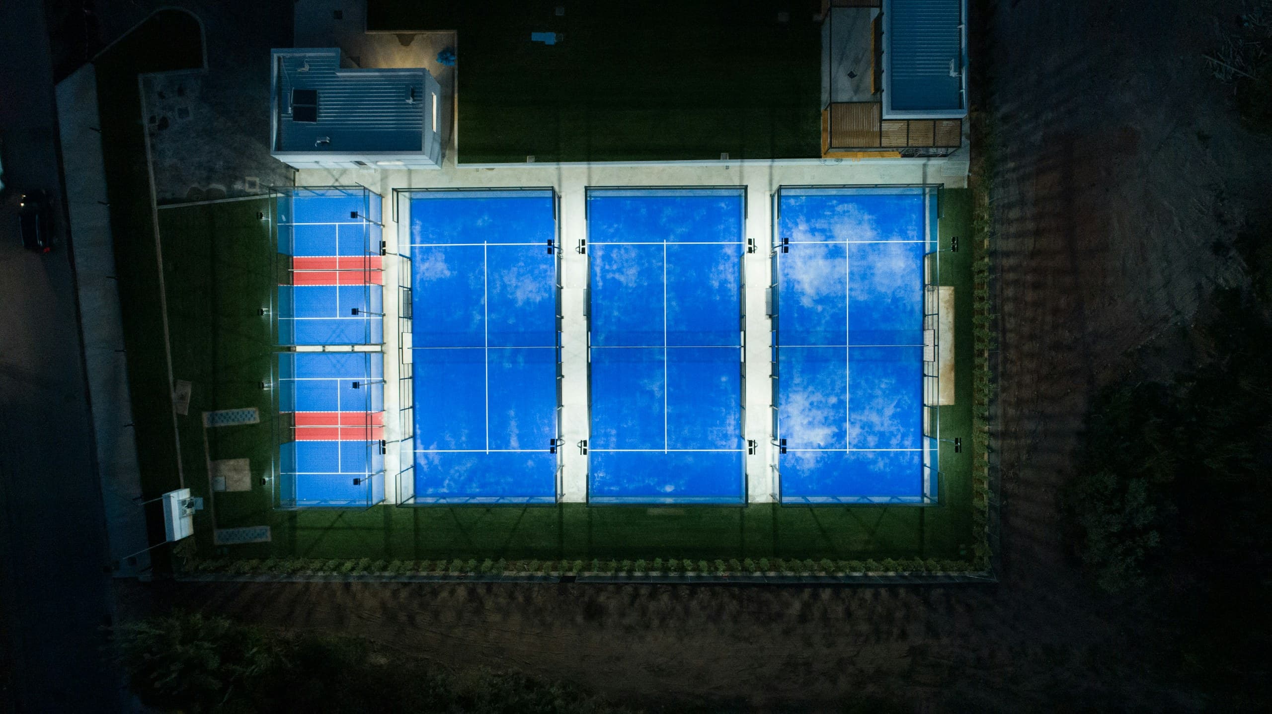 Vue aérienne de nuit d'un complexe de trois pistes de padel éclairées