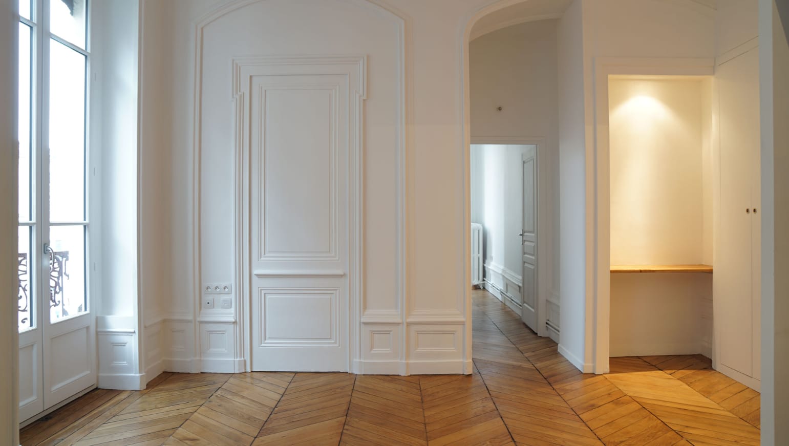Enfilade de portes à moulures blanches et parquet, dans un ancien local commercial transformé en appartement aux Terreaux, Lyon