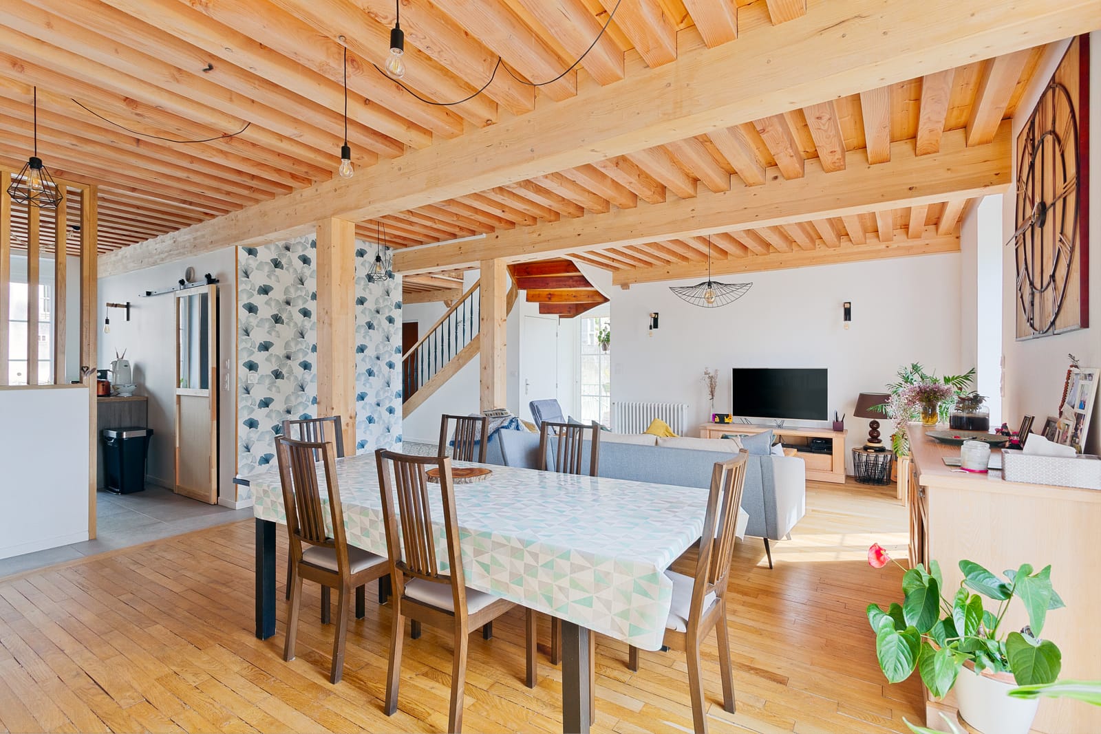 Pièce de vie ouverte sous plafond à la française en bois clair, avec table à manger et parquet, dans une maison rénovée à Pont-d'Ain
