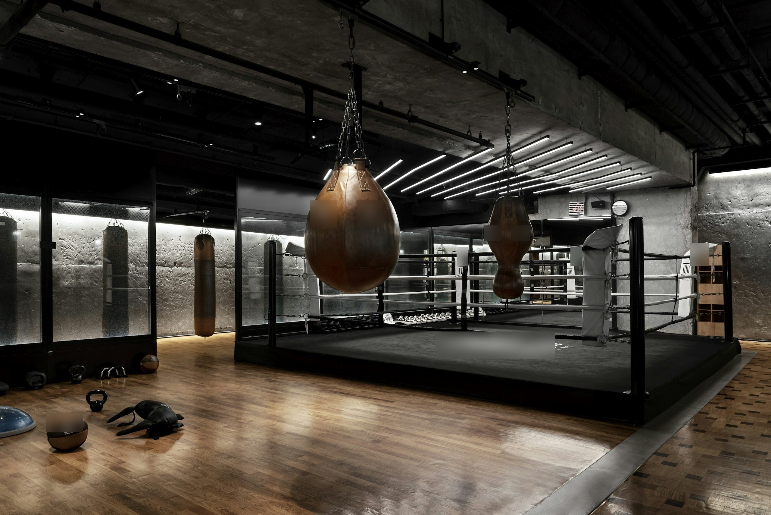 Salle de boxe au ring central, sacs de frappe en cuir et parquet
