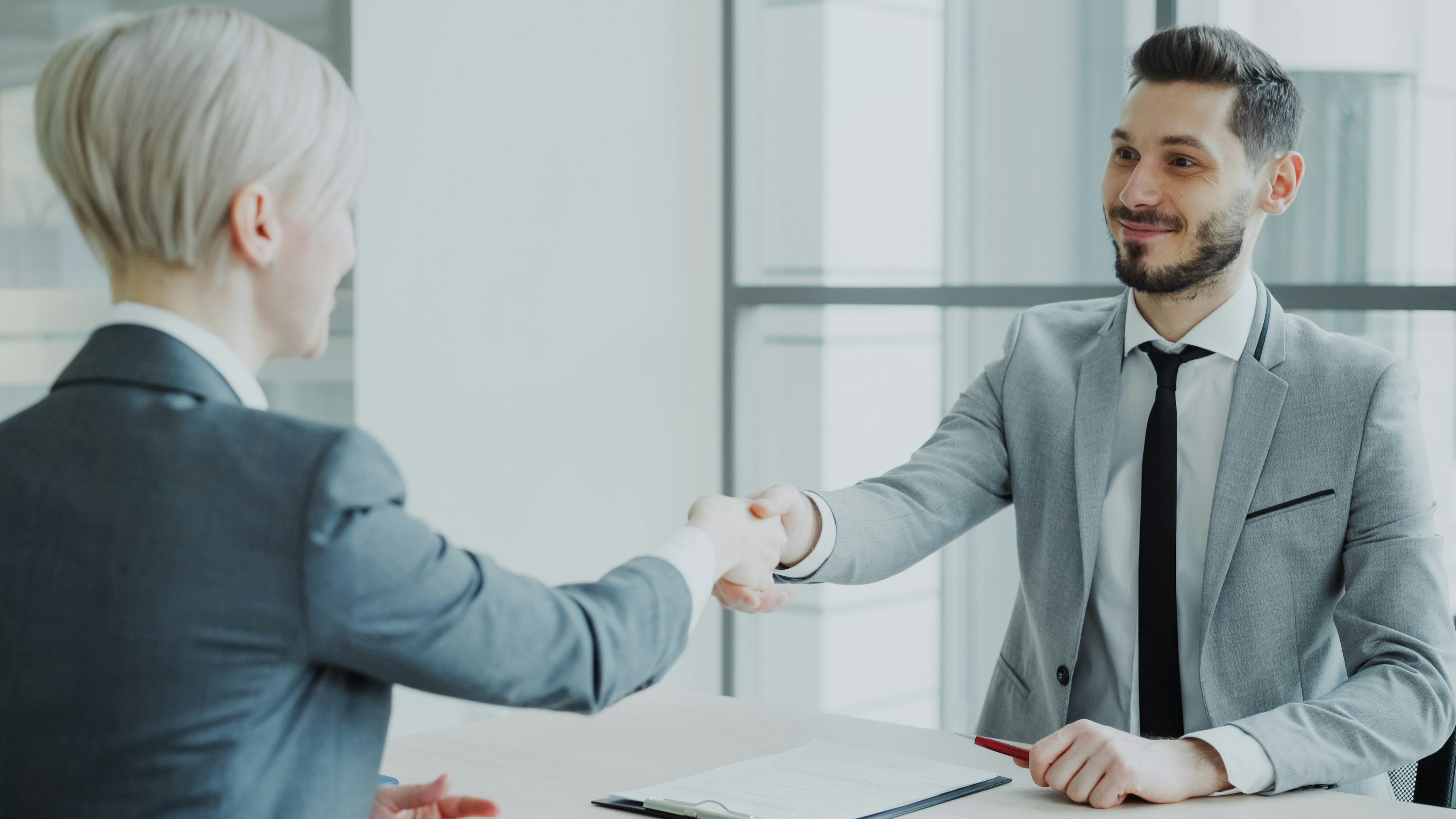 Poignée de main entre un client et son interlocuteur, dans un bureau lumineux