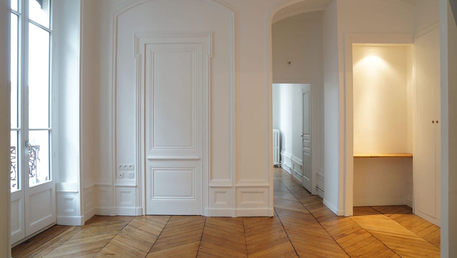 Enfilade de portes à moulures blanches et parquet, dans un ancien local commercial transformé en appartement aux Terreaux, Lyon