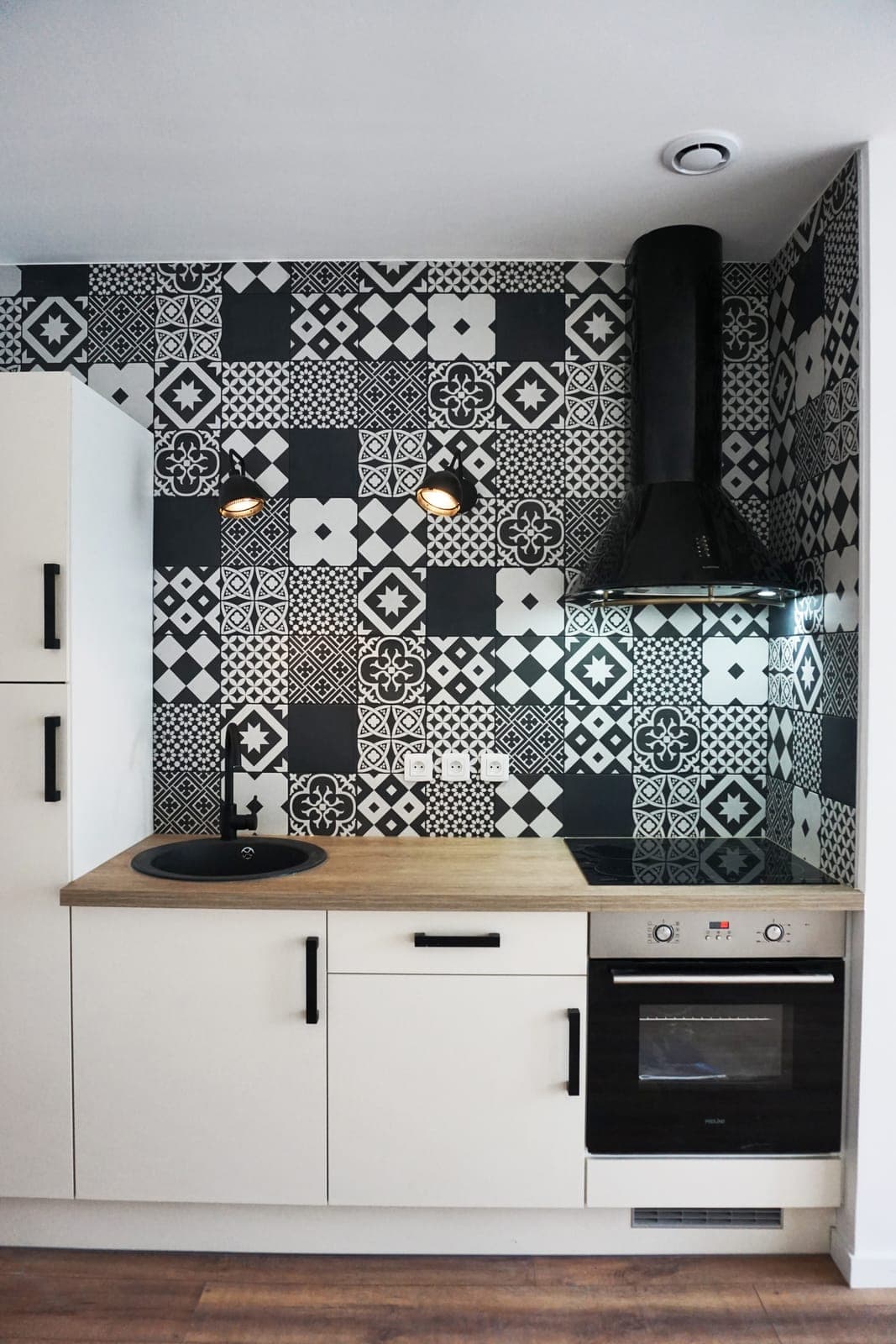 Cuisine blanche avec crédence en carreaux de ciment noirs et blancs, dans un appartement réhabilité à Seyssel