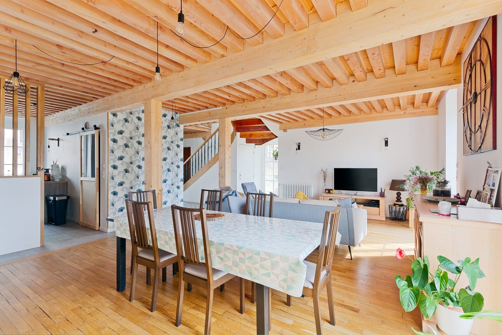 Pièce de vie ouverte sous plafond à la française en bois clair, avec table à manger et parquet, dans une maison rénovée à Pont-d'Ain