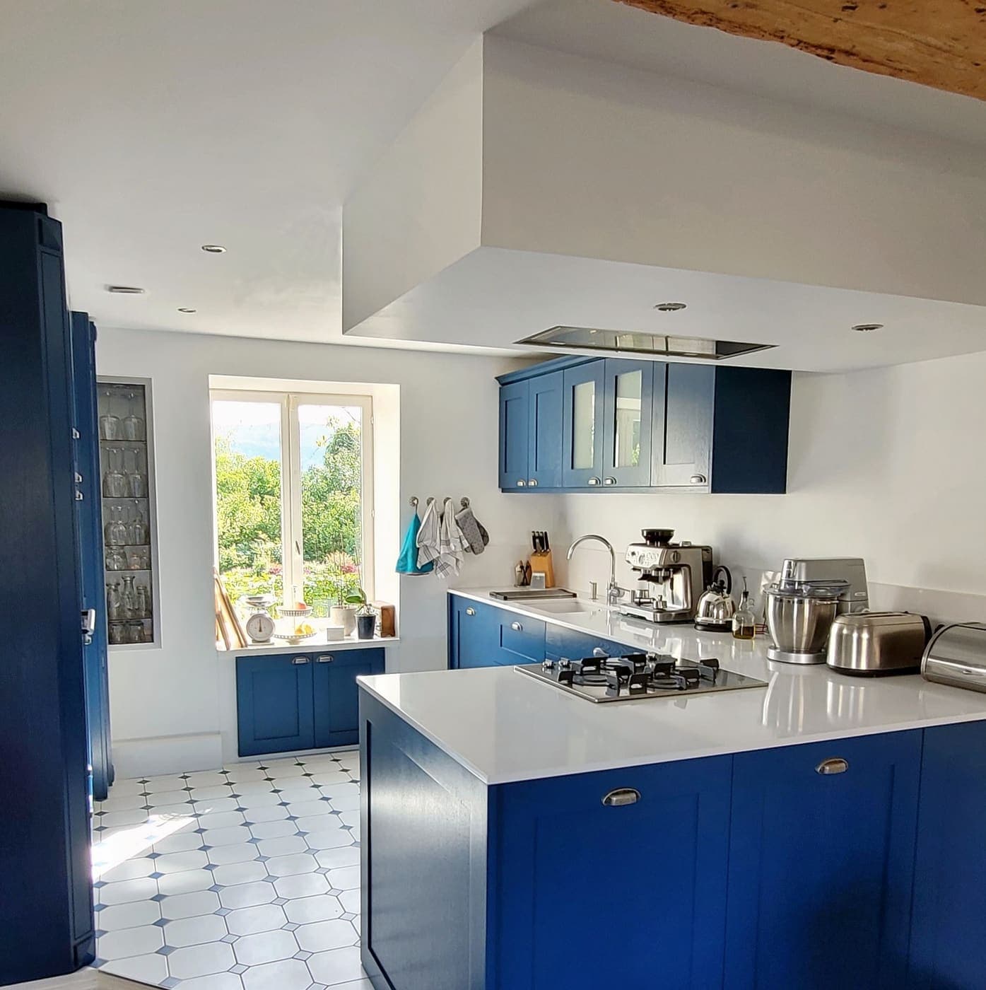 Cuisine bleue avec îlot et hotte intégrée au plafond
